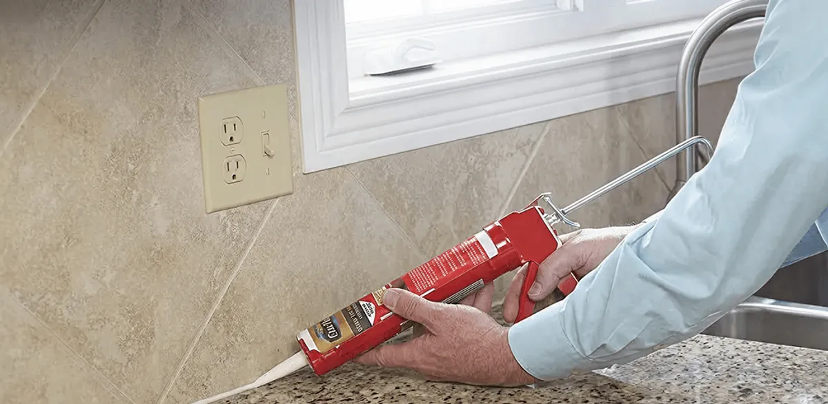 Handyman applying caulk along a kitchen backsplash and countertop seam in Milwaukee, WI