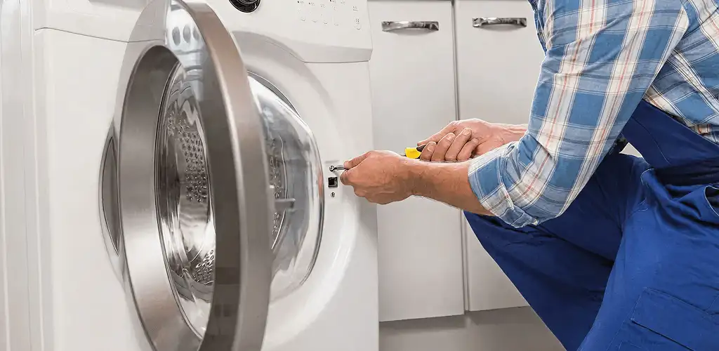 Handyman repairing a clothes dryer and checking electrical connections in Milwaukee, WI