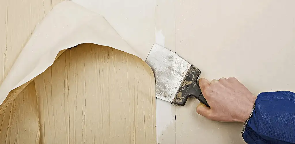Handyman removing wallpaper with a scraper for wall preparation in Milwaukee, WI