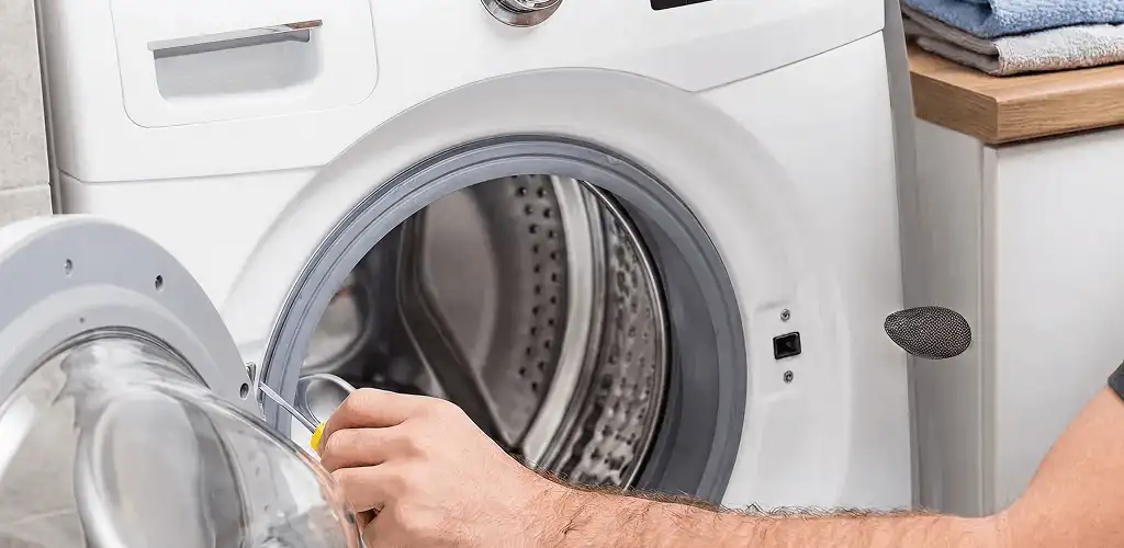 Handyman repairing a front-load washing machine and inspecting the drum in Milwaukee, WI