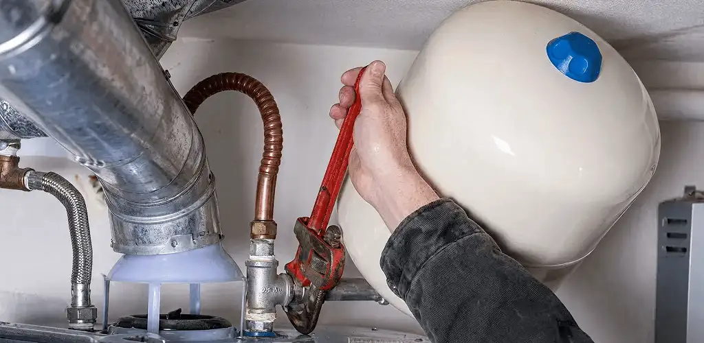 Water heater repair technician tightening plumbing connections near a tank unit in Milwaukee, WI